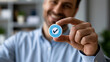 © Nataliya - Businessman showcasing a quality control certification badge against a clean office backdrop, automated process assurance, quality guarantee, manufacturing standards, corporate