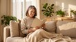 © RicardoLuiz - Middle-aged woman relaxing on a comfortable sofa and reading a book in a sunlit, cozy living room