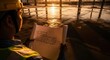 © ELCINDY - Construction Worker Reviewing Blueprint at Sunrise Construction Site