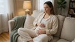 © utaem2022 - Expectant mother cradles her belly while sitting on a cozy sofa at home