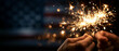© Olga Ко - Burning sparklers in hands against a blurred American flag background. United States 250th anniversary semiquincentennial celebration banner with copy space