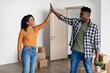 © Prostock-studio - Smiling African American Man And Woman Sharing Joyful Moment By High Fiving Each Other Inside Their New Apartment While Surrounded By Moving Boxes. Excited Young Couple Celebrating New Beginning.