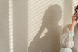 © buritora - A woman standing by a window bathed in the setting sun (model, fashion, light, shadow)