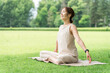 © buritora - Asian women taking deep breaths, stretching, and doing yoga in a park.