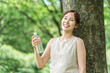 © buritora - A woman drinking water in the forest (hydration, mineral water, sodium)
