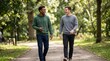 © Juliana - Two young men walking and laughing together on a park path surrounded by trees
