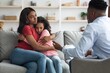 © Prostock-studio - Worried Expression On Black Woman Holding Young Girl During Therapy Session. Both Seeking Emotional Support And Understanding In Cozy Home Setting. Focus On Mental Wellness And Family Healthcare