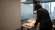 © FrameFlow - Businesswoman in dark suit, with color coded folder tabs, standing and reviewing documents, modern corporate office, corporate business photography