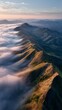 © Andi - Jagged mountain ridge emerging from a sea of clouds at sunrise with golden light illuminating the peaks