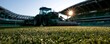 © teostudio - Tractor mowing a sports field at sunrise with stadium seating in the background.