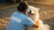 © Iryna - Joyful Samoyed dog receiving hug from Asian volunteer woman outdoors, animal welfare and pet adoption in shelter courtyard