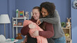 © Krakenimages.com - Plus size woman cradles swaddled baby with bare hands as partner reaches over to touch the infant in a building; tenderness care love.