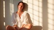 © svastix - A serene scene capturing a woman in a light dress bathed in soft sunlight, casting elegant shadows on the wall, evoking peace and tranquility in the atmosphere.