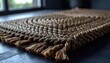 © Nazaba - Close-up view of a rustic braided jute rug with fringed edges showcasing natural texture and warm earth tones.
