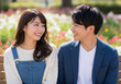 © Anoconone - 色鮮やかな花々に囲まれた公園のベンチで見つめ合う男女と女性