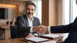 © Syed - Mature senior business man shaking hands with partner at boardroom table signing contract deal. Latin indian CEO businessman entrepreneur handshake meeting professional agreement, banner copy space