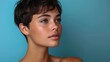 © Zypher-graphics - Close-up portrait of a young woman with a short pixie haircut and blue eyes on a turquoise background