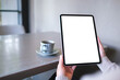 © Farknot Architect - Mockup image of a woman holding digital tablet with blank white desktop screen in cafe