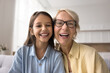 © fizkes - Happy elderly 60s grandmother in glasses sit on sofa with cute preteen 12s granddaughter laughing while talking with relatives via videocall app or record videovlog, webcam view, head shot portrait