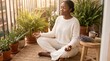 © NurIzzati - Black Woman Meditating on Balcony for International Self Care Day