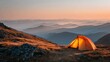 © Harry - Bright orange camping tent sitting on a high grassy mountain ridge during a beautiful soft golden hour sunset landscape scene