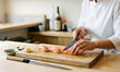 © BongoStock - Chef preparing sushi on a wooden cutting board in a kitchen with a knife and ingredients