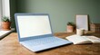 © Sariyono - Modern Laptop on Wooden Desk with Open Book and Potted Plants in Cozy Workspace.