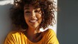 © The Little Hut - Close-up portrait of a happy young woman with curly hair smiling in warm sunlight, conveying positivity and joy
