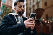 © BullRun - Joyful woman looking away while holding smartphone, happy female user enjoying digital lifestyle, wireless communication and social network concept, urban setting, authentic representation.