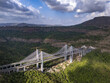 © AmazingAerialAgency - Aerial view of the Mumbai-Pune Expressway Missing Link Project cable-stayed bridge under construction, spanning a lush green valley with surrounding hills in Khopoli, Maharashtra, India.