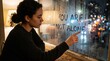 © Kleber - Young woman touches condensation on window with message You Are Not Alone during a rainy night in the city
