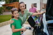 © Halfpoint - Mother and girl charging electric car while family prepares for summer trip.