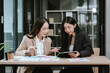 © Kieng - Two businesswomen reviewing financial reports and discussing strategy in a modern office, collaborating on data analysis, planning, and decision-making during a professional meeting.