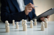 © Custard Pixel - Human resources management concept with wooden figures and HR professional analyzing workforce data supporting employee assessment team planning talent strategy and organizational success