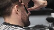 © volha_r - Professional barber performing precise beard shaving with classic straight razor, working in modern barbershop with skilled grooming technique