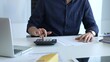© volha_r - Businessman in a blue shirt examining financial documents at an office desk, using a calculator amidst paperwork and folders. Audit and taxes, business concept