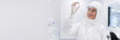 © SerPak - Scientist in a white protective suit and gloves holds a vial while smiling in a modern laboratory. Laboratory research and safety.