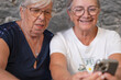 © luciano - Senior friends enjoying digital connection, smiling faces looking at smartphone, sharing content and laughing, embracing modern technology and togetherness