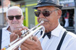 © luciano - Senior adult street musician playing trumpet for an audience, entertaining people with jazz music performance outdoors, celebrating culture and passion for sound