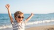 © LinearAndLoom - Happy boy with arms raised wearing sunglasses on tropical beach