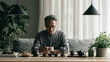 © AS_SleepingPanda - A focused individual works intently at a wooden desk in a bright room