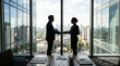 © Sanjit - Two professionals shaking hands in silhouette against a bright conference room window overlooking a sunlit city, representing a successful business agreement or corporate partnership.