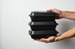 © miss irine - Hands hold stack of black meal prep containers. Takeaway food boxes for delivery service or home cooking. Disposable packaging for lunches or dinner.