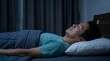 © Николай Срибяник - Asian man sleeping peacefully on his back in a dark bedroom at night.