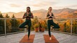 © Николай Срибяник - Diverse women performing yoga tree pose on outdoor balcony with mountain view.