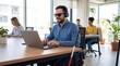 © Christos - Blind professional using laptop with headphones in bright accessible coworking office space