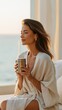 © The Little Hut - Serene woman in a robe enjoying a warm beverage by the ocean at sunrise, embodying peace and relaxation