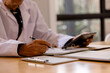© Smallroombigdream - reviewing patient records and using a digital tablet in a healthcare office. doctor completing medical documentation, clinical administration, and modern healthcare management.
