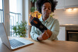 © ingoodtime - Focused woman adjusting orthopedic wrist brace while sitting at table with laptop. Concept of rehabilitation, injury recovery, carpal tunnel syndrome, chronic pain management and healthcare support.
