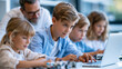 © Nataliya - Anonymous STEM teacher overseeing a robotics coding activity with a group of diverse primary students at desks with laptops, modern education concept, faceless, defocused, with